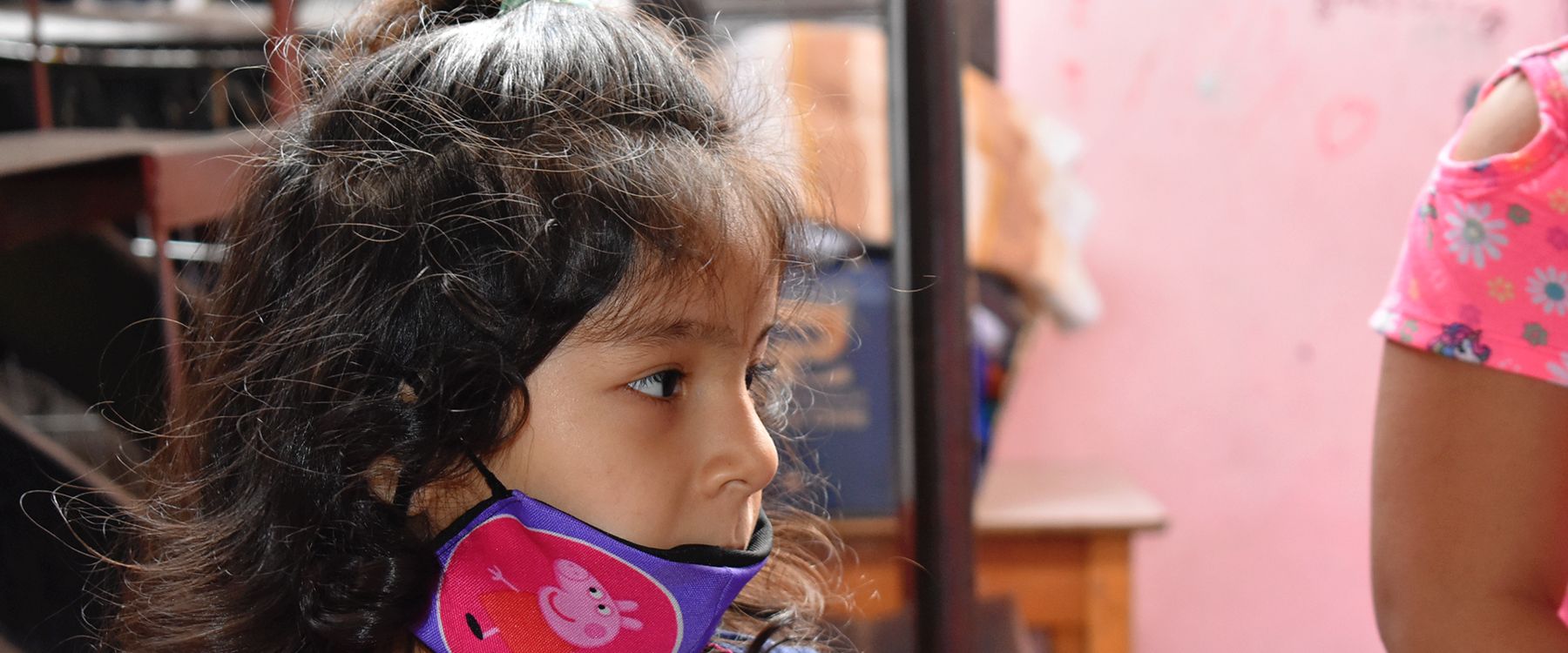 Una niña de perfil con mascarilla, mirando hacia un lado