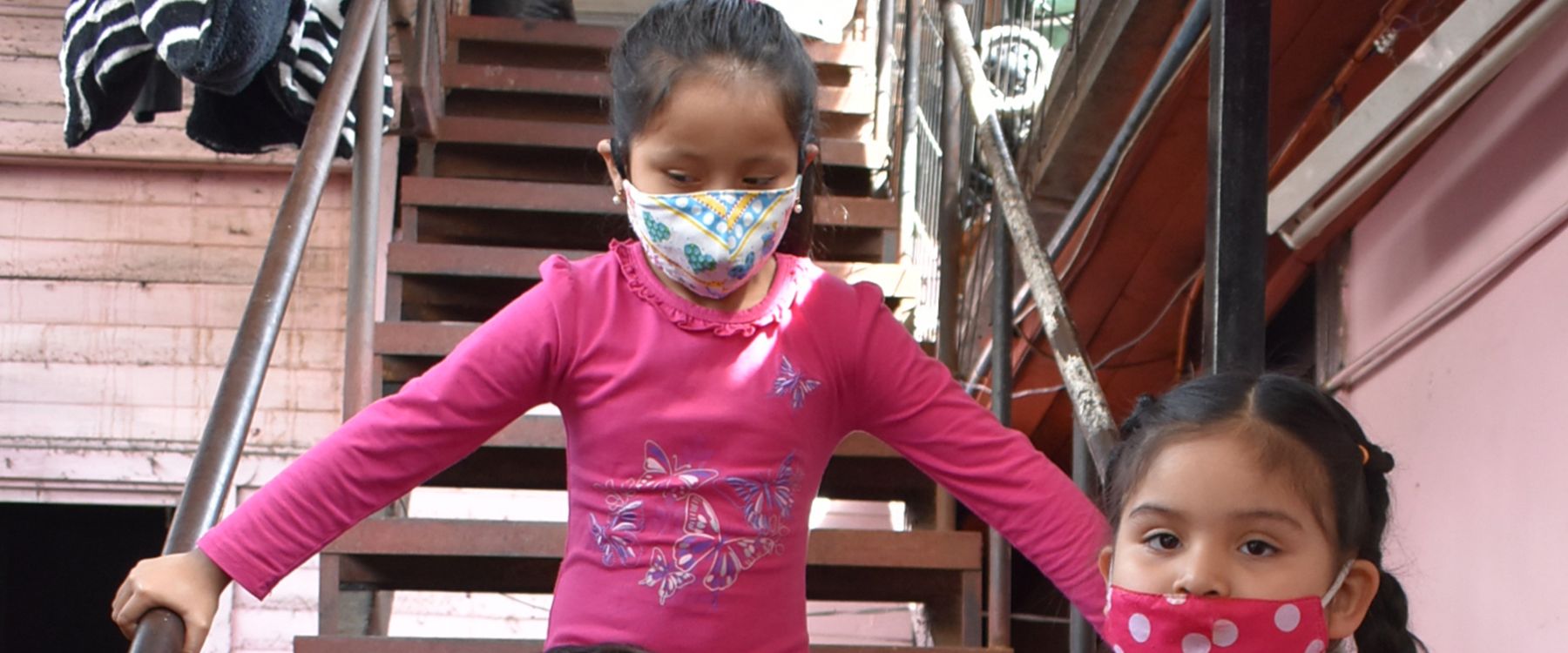 Dos niñas bajan la escalera de la sede con mascarillas