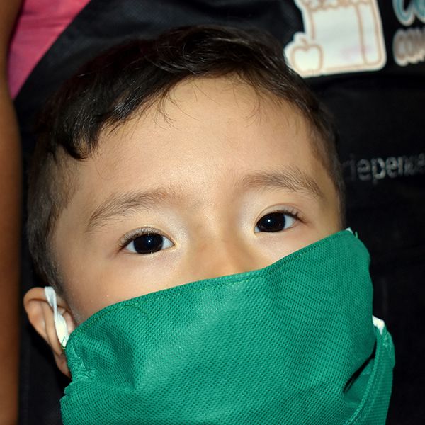 Niño con mascarilla verde mira a la cámara